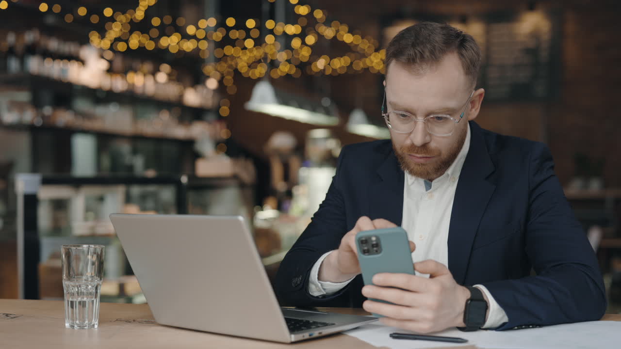 Man using smartphone and laptop in a cafe