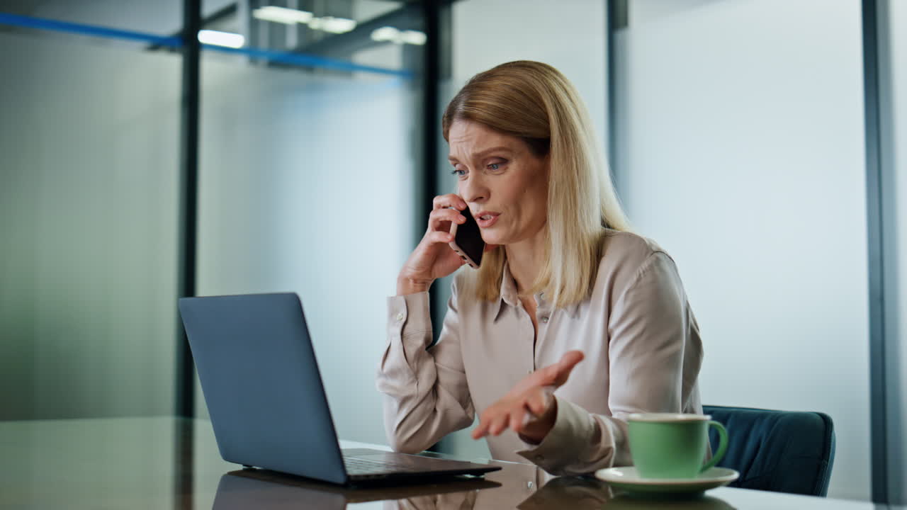 Primo piano di una donna irritata che discute al telefono sul posto di lavoro. Una donna furiosa litiga al cellulare.