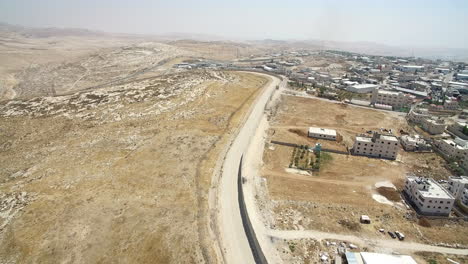 aerial view of a road separating a desert landscape from a middle eastern town