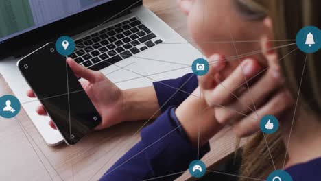 animación de una red de iconos de los medios sobre una mujer caucásica usando un teléfono inteligente y una computadora portátil