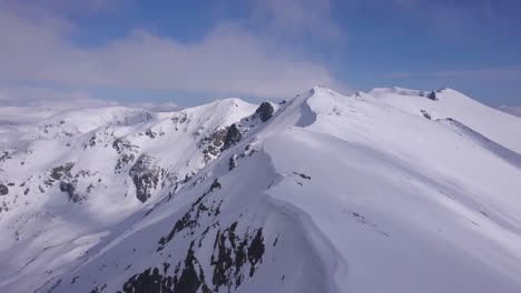 Beautiful-snow-covered-mountain-peaks-and-ridge-with-cornice-of-white-snow-hanging-over-ledge