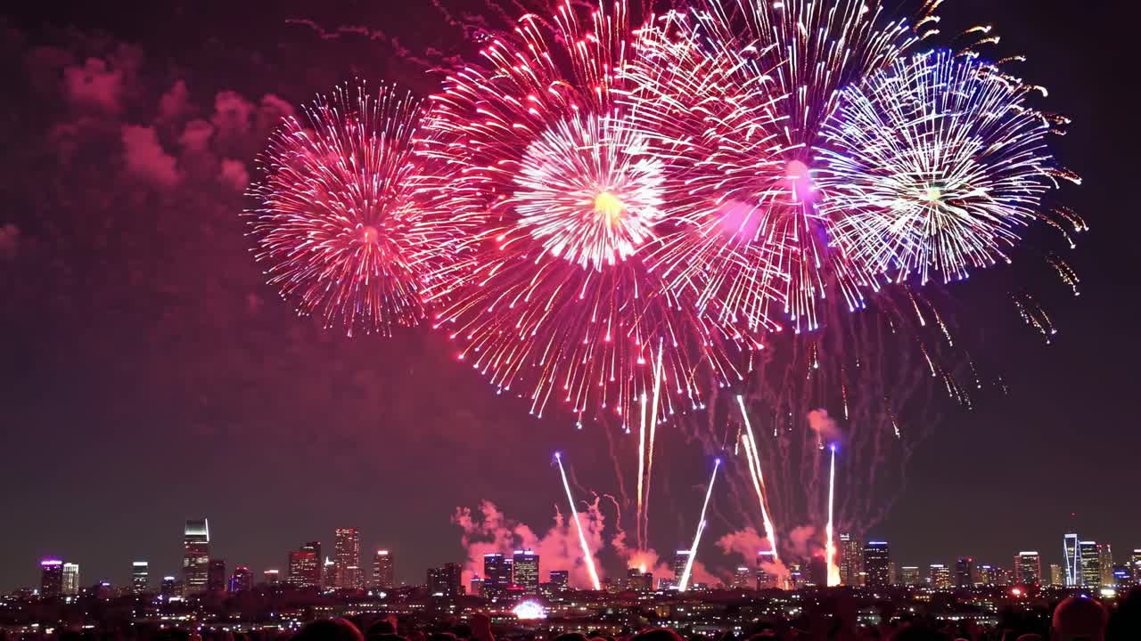 Colorful fireworks light up the night sky over a city skyline, creating a vibrant and festive atmosphere during a special event celebration
