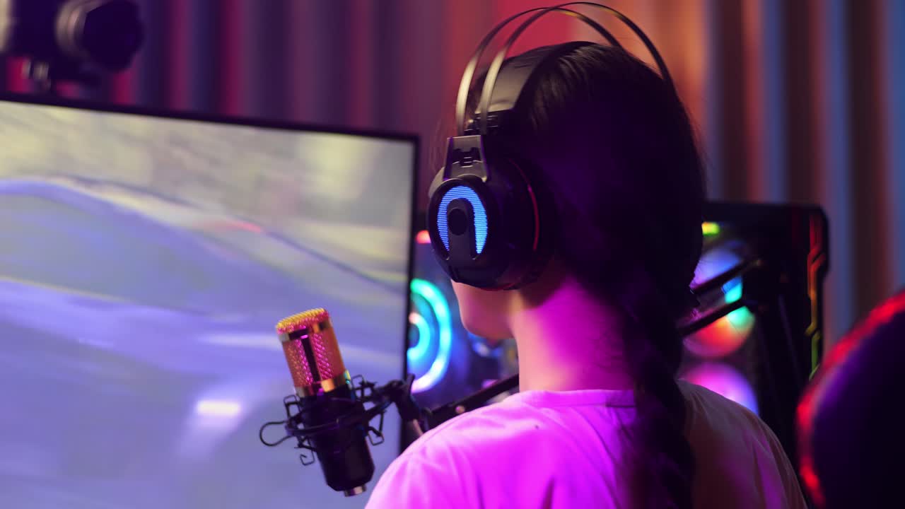 vista de atrás de cerca de la chica asiática streamer gritando gol y bailando celebrando ganando juego de carreras de coches en computadora personal. videojuego de transmisión en vivo, escritorio iluminado por luz de tira de led rgb