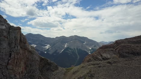 High-alpine-mountain-aerial-flies-over-saddle-on-rocky-summit-ridge