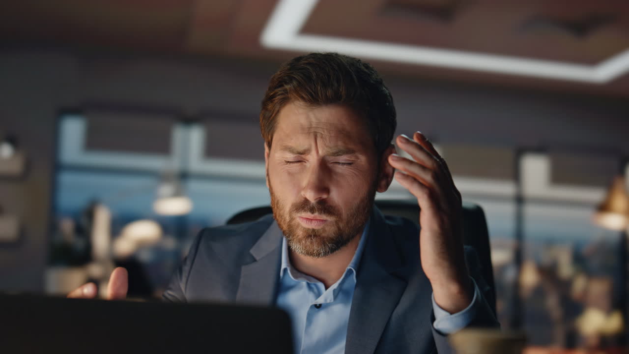 Upset businessman touching head in office closeup. Nervous man feeling stress