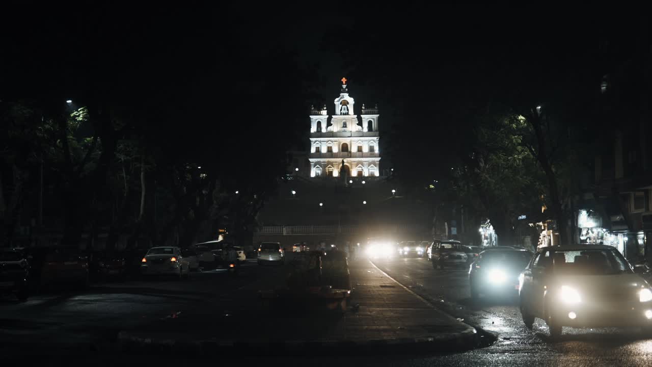 vista nocturna de un templo e iluminación en la parte frontal del templo desde la distancia mientras los autos pasan por la carretera