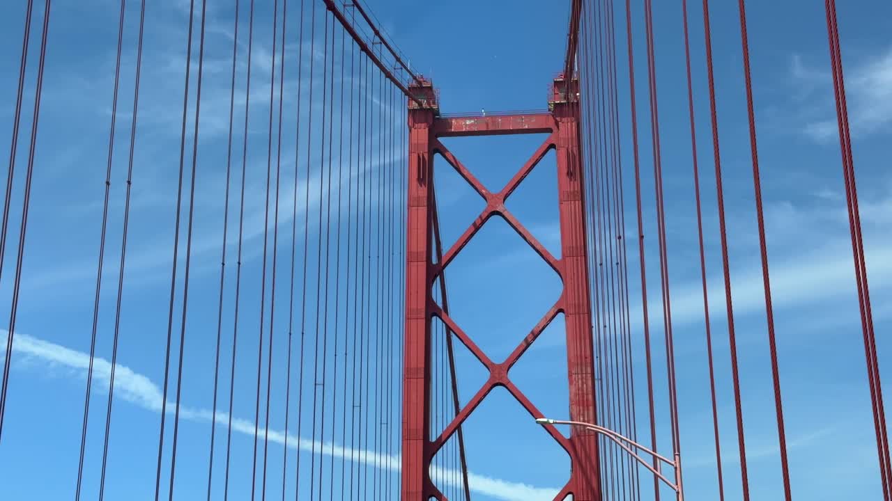 Driving Under a Red Suspension Bridge Against Blue Sky