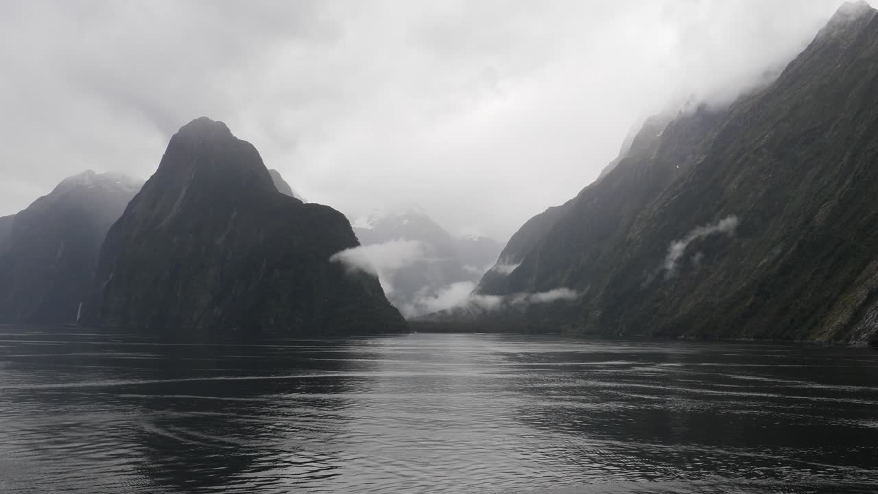 Scenic cruising at Milford Sound (Piopiotahi), Fiordland National Park on the South Island of New Zealand. Milford Sound surrounded by looming mountains and impressive sheer rock faces.