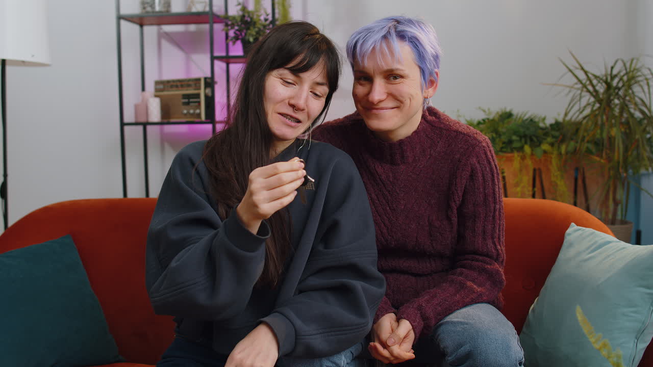 Lesbian women family couple lifting hand showing keys of new home house apartment buying or renting