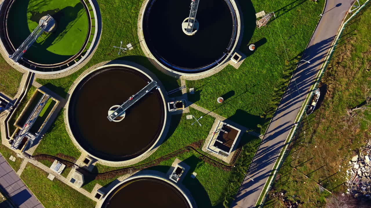 Water treatment facility near a road with several tanks surrounded by grass in daytime