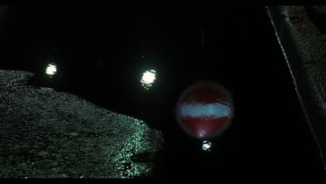 reflection in pothole filled with water of no entry sign on a road at night in sheffield, south yorkshire