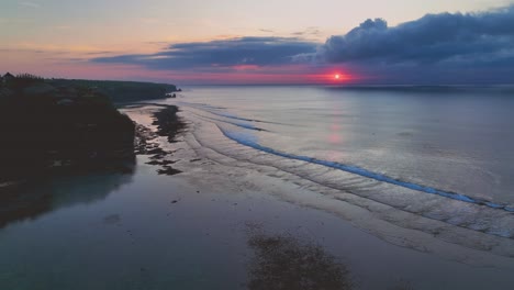 calming drone clip showing quiet beach in bali, indonesia, with beautiful pink sunset over calm ocean