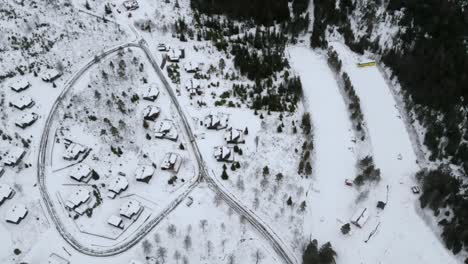 disparo de avión no tripulado de una pequeña aldea de cabaña en una ladera con nieve