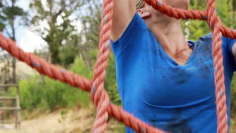 mujer en forma subiendo a una red durante una carrera de obstáculos