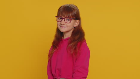 Cheerful-lovely-young-preteen-child-girl-kid-smiling,-looking-at-camera-on-studio-yellow-background