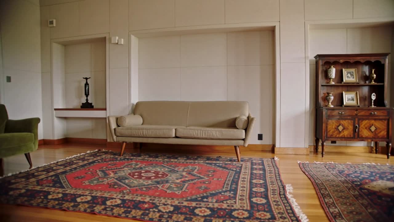 Panning left camera revealing midcentury sofa in living room, showing Persian rugs and cabinet