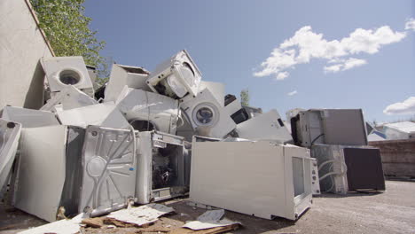 dramatic low angle slider of discarded washing machines and appliances at dump