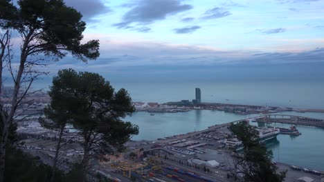 vista del puerto de barcelona desde las alturas de montjuïc en una tarde parcialmente nublada