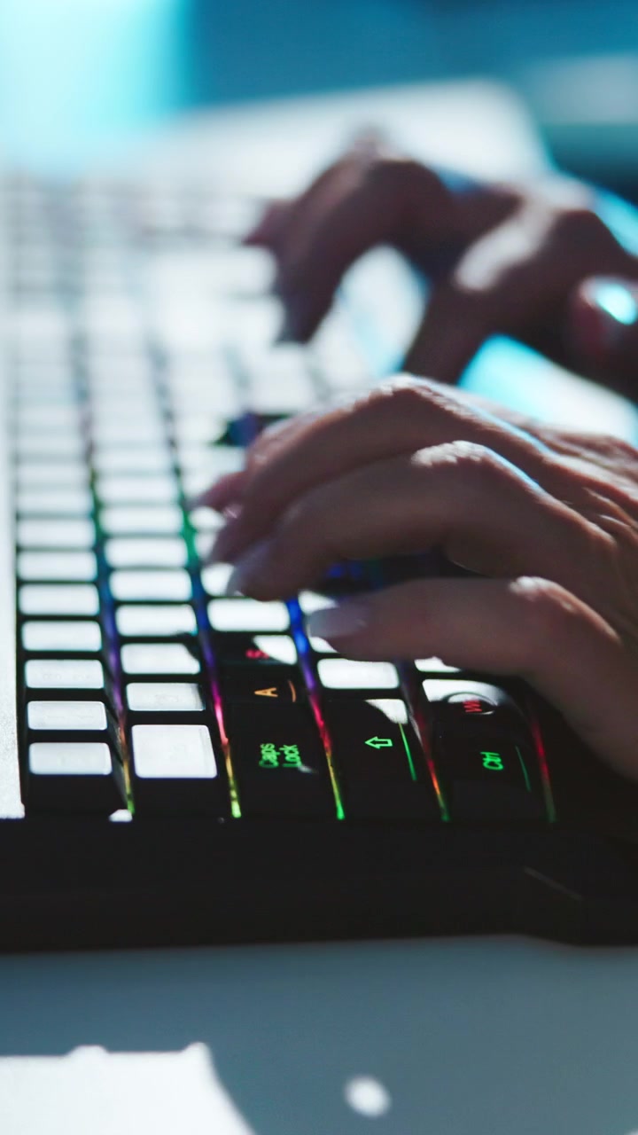 Primo piano di mani che digitano su una tastiera meccanica retroilluminata RGB