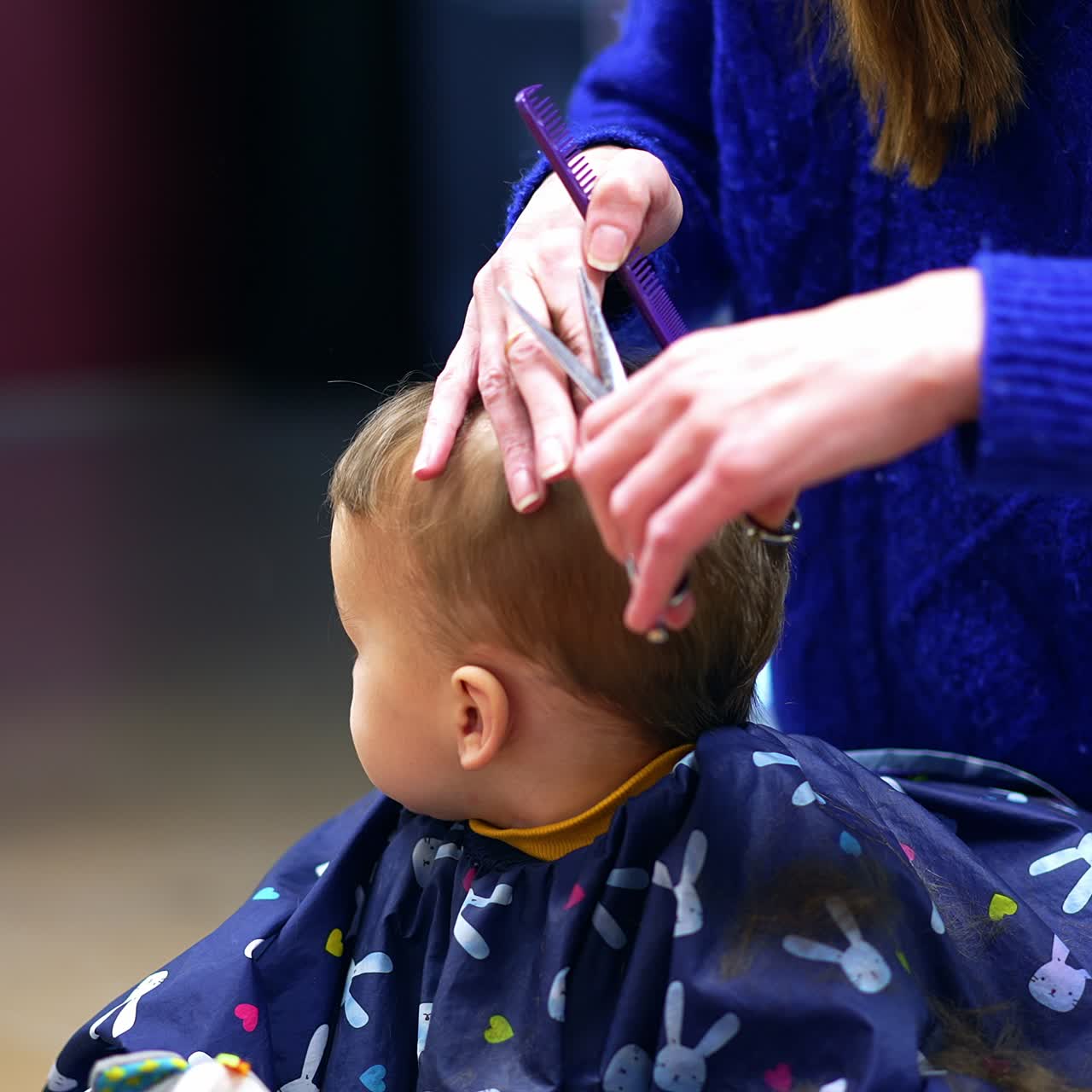 Un bel bambino in un salone di parrucchiere. Il bambino seduto, tranquillo, si guarda intorno. Sfondo sfocato
