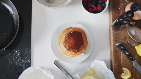 overhead shot of woman in kitchen serving pancakes or crepes for pancake day