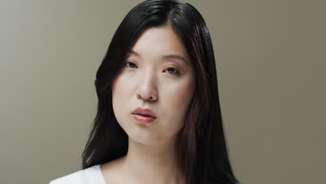 asian woman with black hair and make up looking at camera, copy space, slow motion