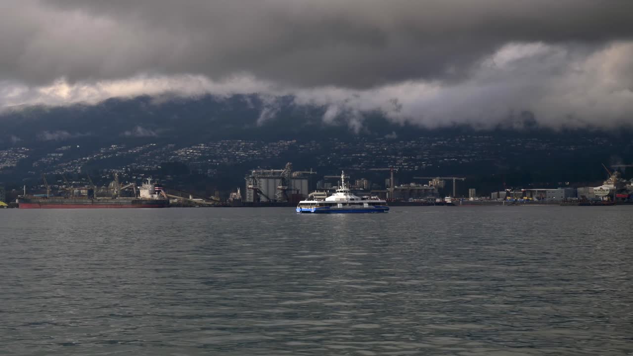 A Ferry Gliding Across the Harbor Under Brooding Mountain Clouds - Aerial Drone Shot