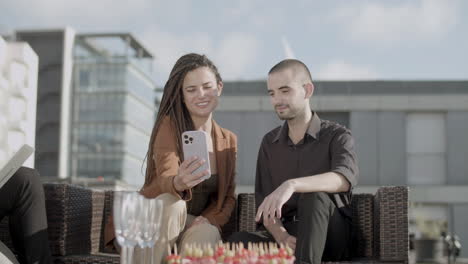 front view of cheerful coworkers looking at phone screen