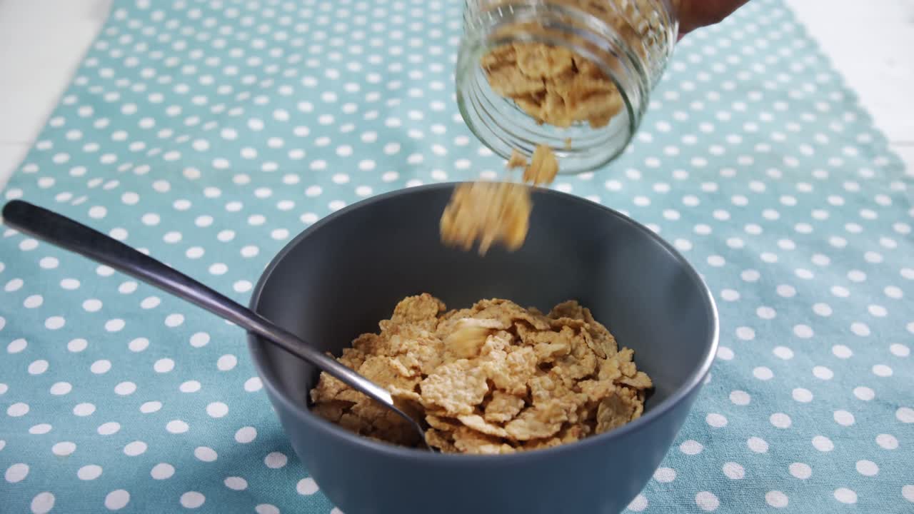 manos derramando copos de maíz de trigo en el cuenco 4k