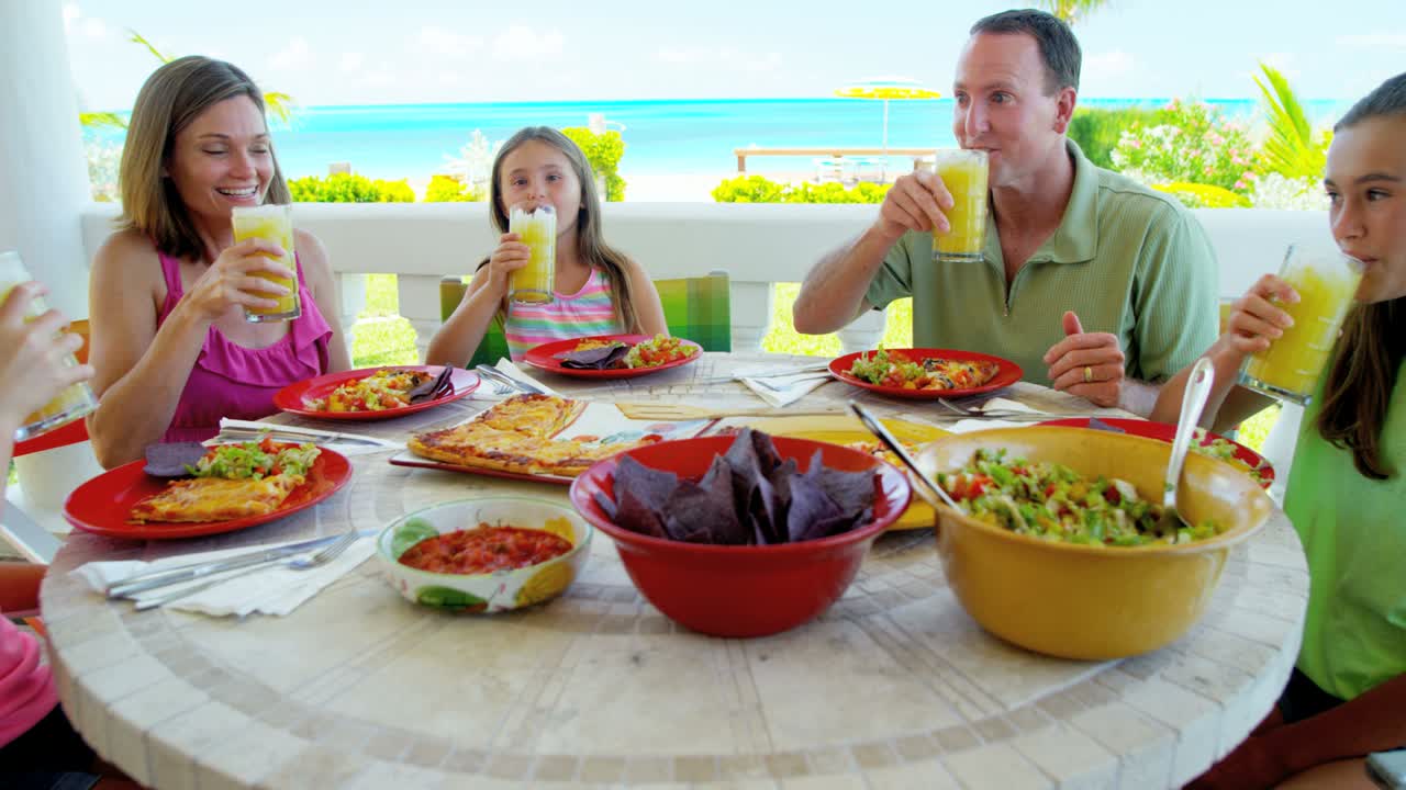Kaukasisk familie spiser lunsj utendørs på strandterrasse