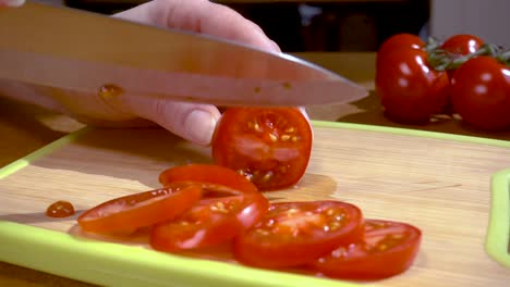 knife cuts tomato on wooden board slow motion with rotation tracking shot.