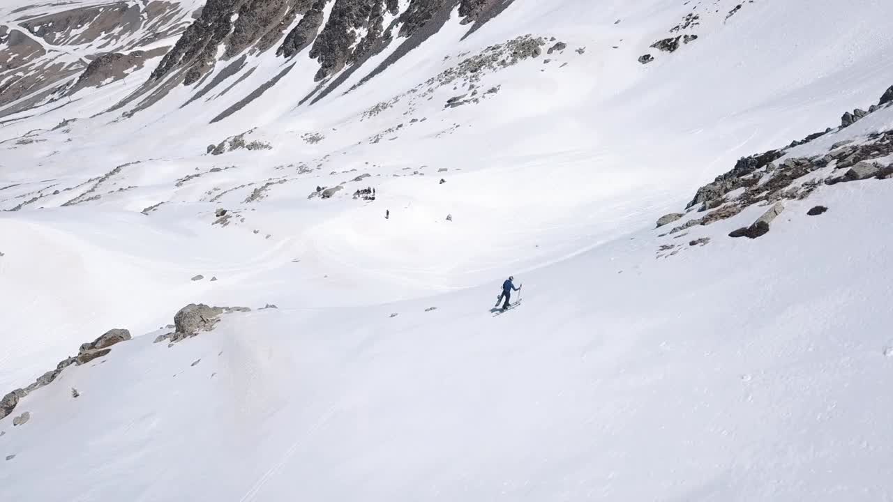 vista aérea de un hombre escalando una montaña con esquís en la nieve