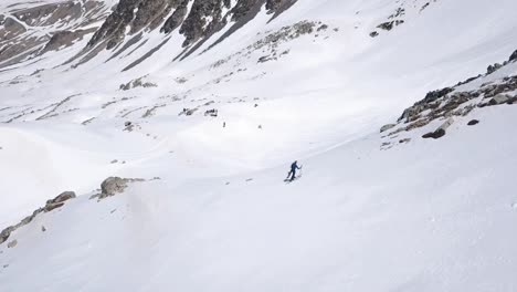 aerial view of a man climbing up a mountain on skis in the snow