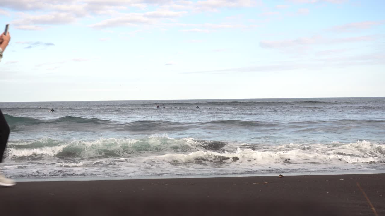 서퍼 와 관광객 들 이 있는 검은 모래 해변
