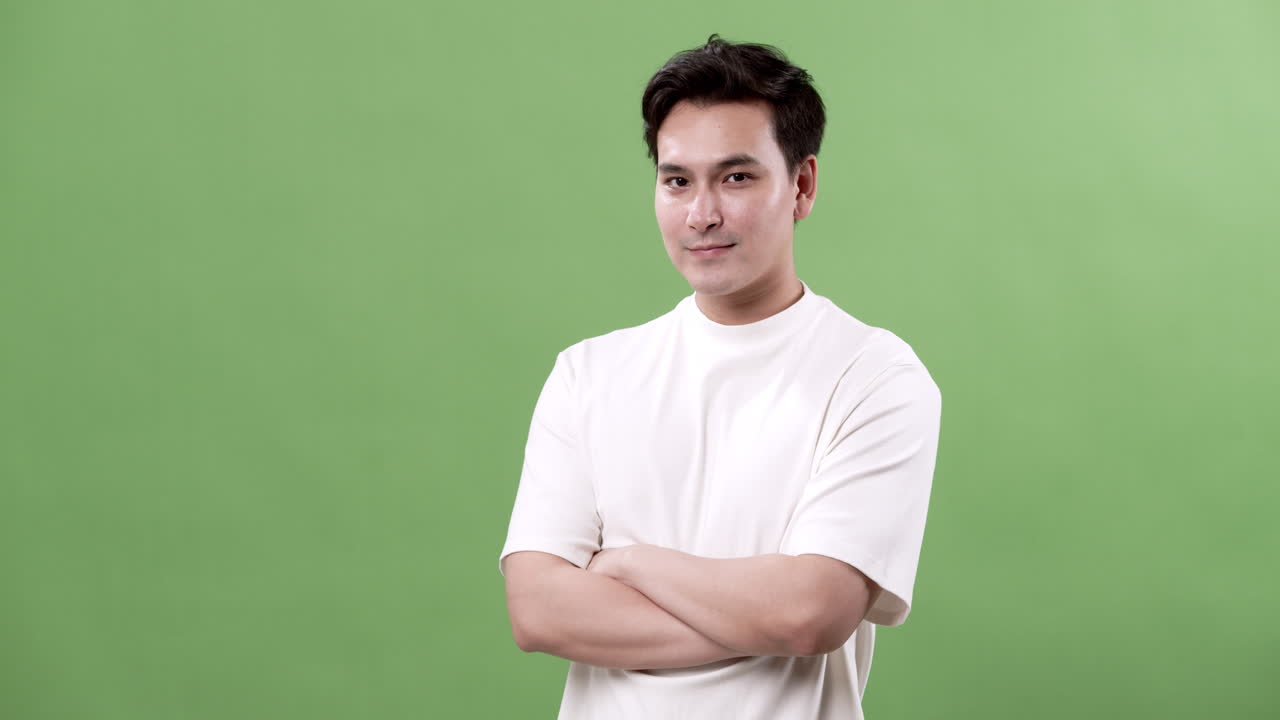 Confident young man standing with crossed arms, embodying determination and ambition in business, all against a vibrant green background.