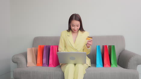 woman use of laptop computer for shopping online lots of shopping bag on sofa