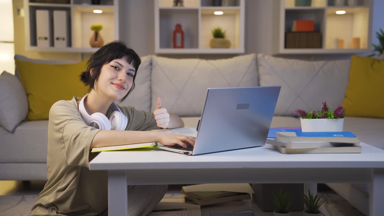 성공한 학생은 집에서 공부하는 동안 미소 짓고 카메라를 쳐다본다.