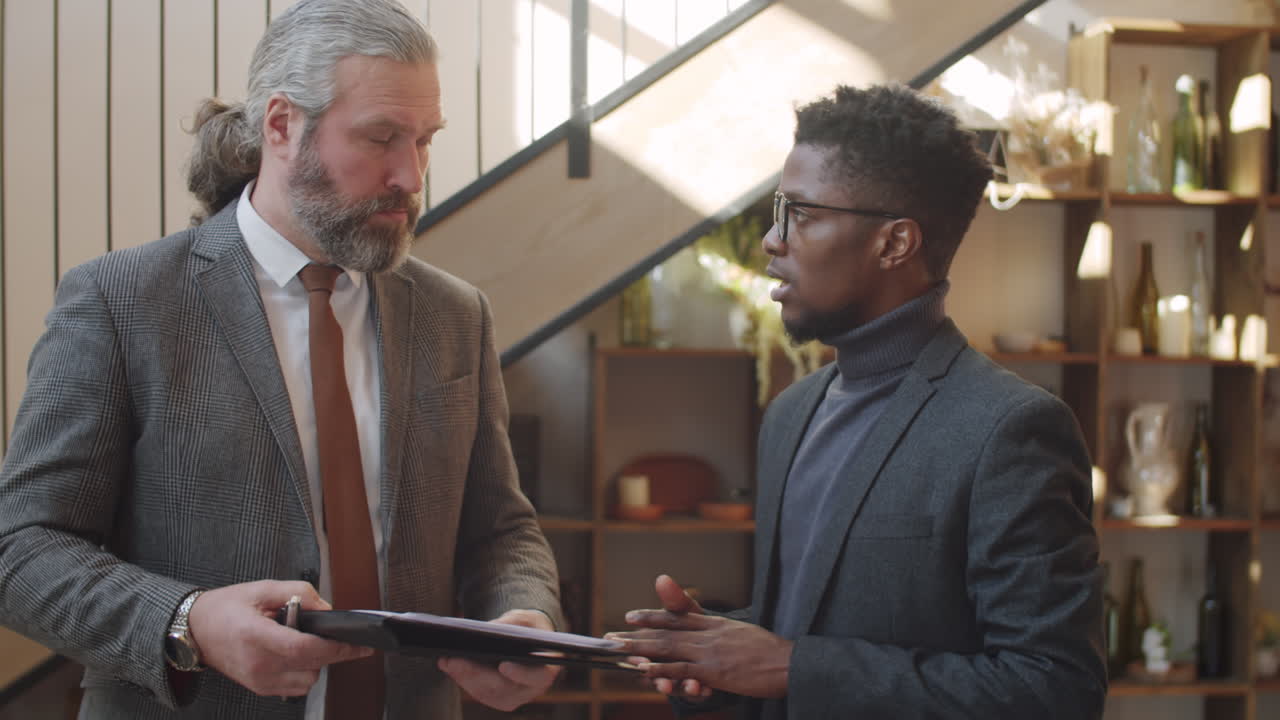 Multiethnic Male Colleagues Discussing Papers in Restaurant