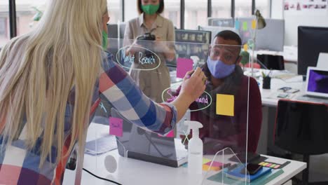 diverse business people wearing face masks using a board in modern office