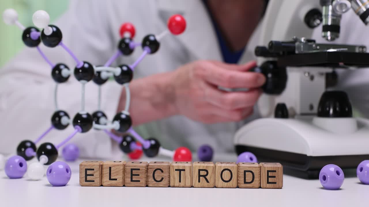 Blocchi di legno formano la parola "elettrodo" vicino a un microscopio in laboratorio.