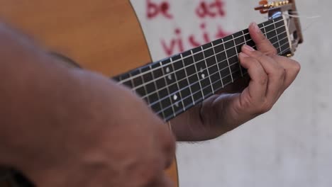 Close-up-of-playing-guitar-outside-with-graffiti-in-the-background