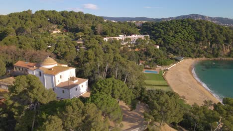 aerial-image-with-drone-of-lloret-de-mar-virgin-beach-with-green-vegetation-in-mediterranean-church-overlooking-the-sea-in-the-mediterranean-santa-cristina-lloret-de-mar-spain-europe
