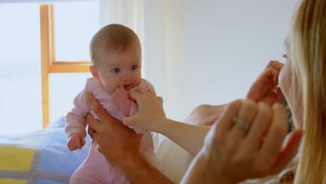 mid adult caucasian parents playing with baby on bed in a comfortable home 4k