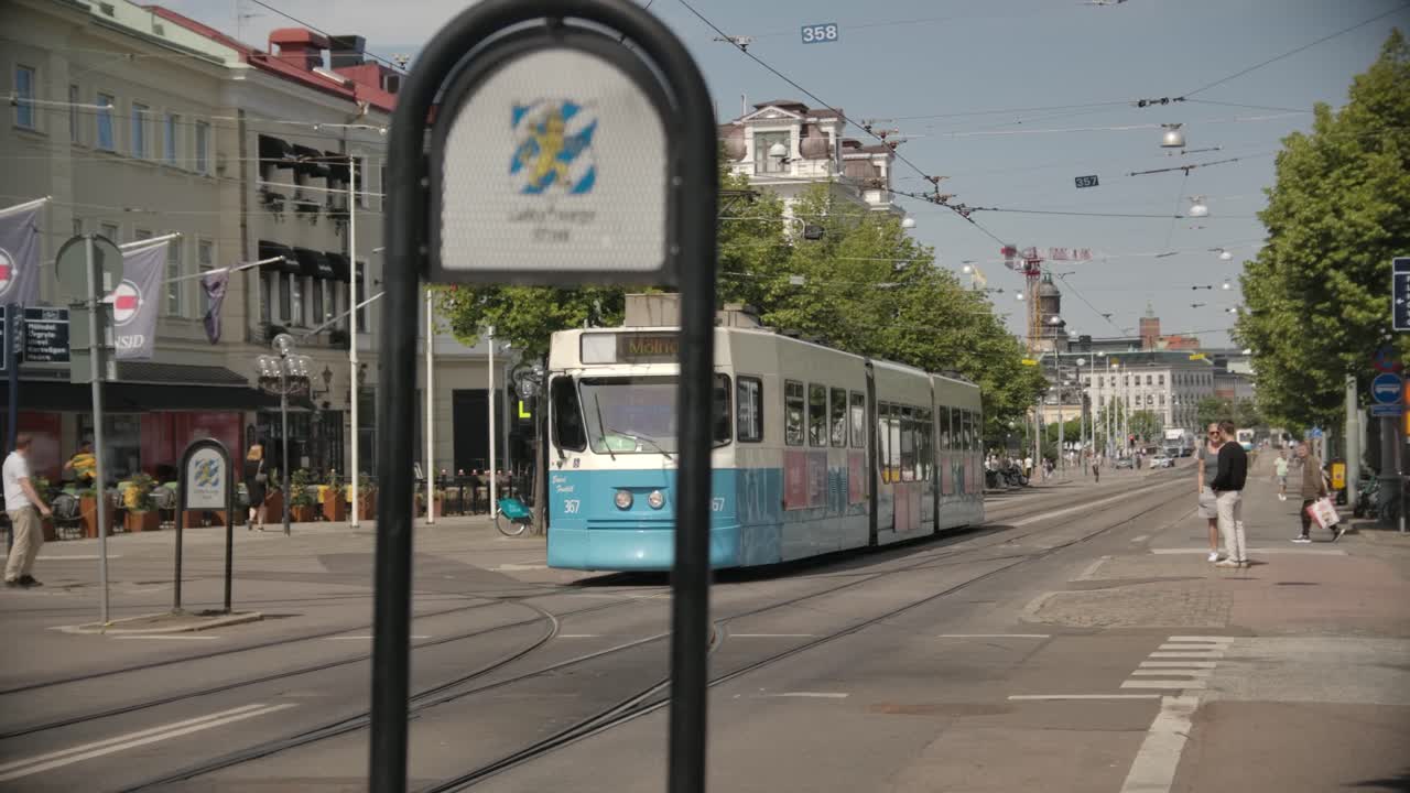 A blue and white tram on a city street in Gothenburg, Sweden