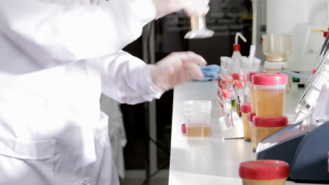 In-a-science-laboratory,-a-scientist-is-pouring-waste-water-into-a-measuring-test-tube,-then-into-a-separate-tube-for-further-analysis