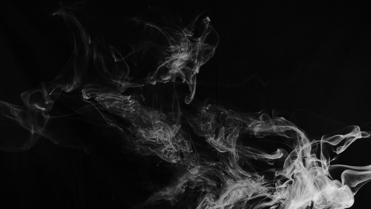 Volute di fumo eteree in slow motion avvolgono l'inquadratura.
