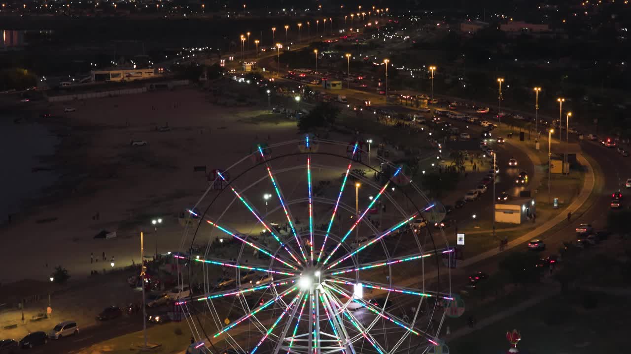Close up aerial of Ferris wheel at Ecko Park with Costanera Avenue at night, Asuncion