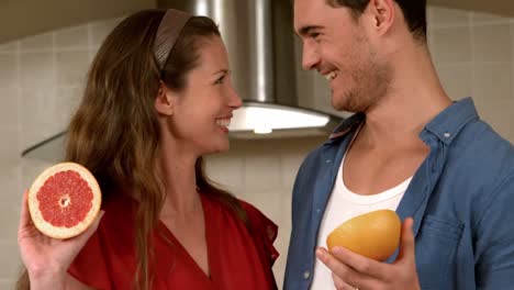 smiling young couple holding half of grapefruit