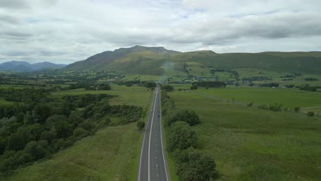 High-altitude-view-of-rural-highway-A66-running-towards-mountain-Blencathra-on-cloudy-summer-day