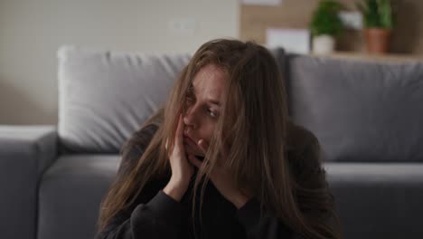 Caucasian-broken-woman-sitting-at-the-floor-in-living-room.